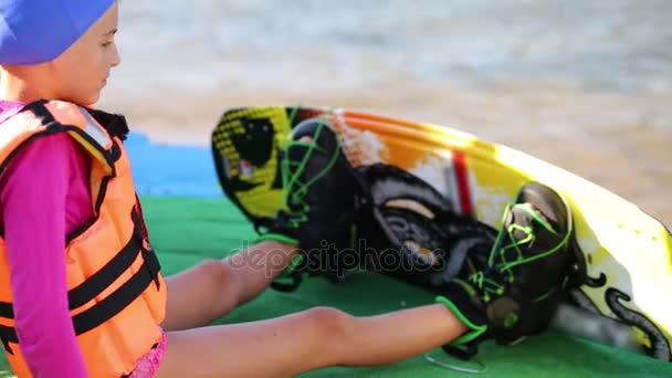 Meisje Met Wakeboard Voeten Aanraken Van Zijn Handen Zittend Wal — Stockvideo