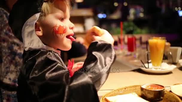 かわいい男の子の頬に描かれたクモの衣装でパンケーキを食べるし ジュースを飲む — ストック動画