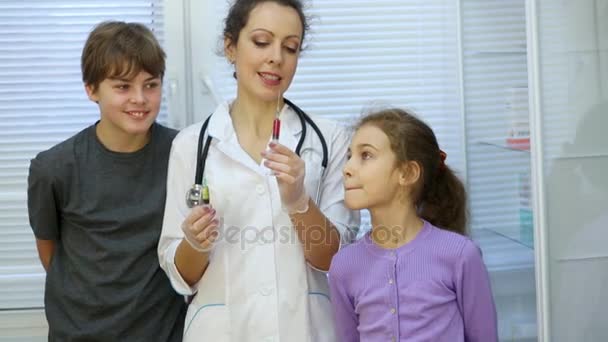 女医薬と注射器 本を保持し それらについての近くに立つ子どもに指示 — ストック動画