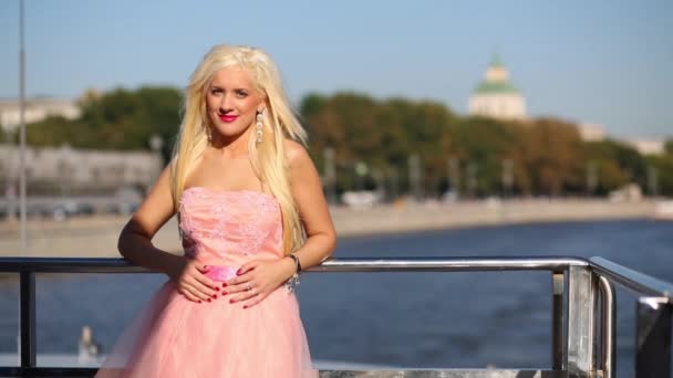 穿粉红色衣服的女孩站在船的扶手上航行在河上 — 图库视频影像