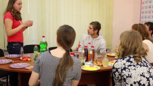 六青少年坐在桌上玩哑剧游戏在生日 女孩描绘对象 — 图库视频影像