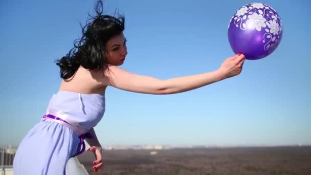 穿蓝色衣服的黑发妇女在屋顶的篱笆上拿着气球 — 图库视频影像