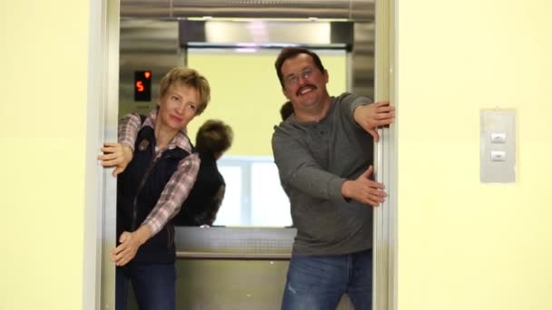 一个男人和一个女人代替手 防止电梯门关闭 — 图库视频影像