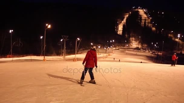 Mulher esquiador para baixo na encosta na noite de inverno — Vídeo de Stock
