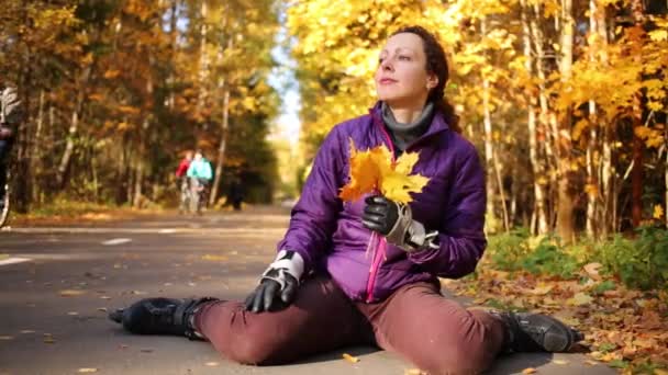 Женщина Роликовых Коньках Сидит Дороге Листьями Руках — стоковое видео