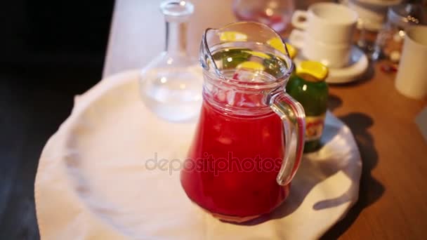 テーブルの上の氷で赤いジュースを持つ投手のクローズ アップ — ストック動画