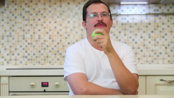 Muž Brýlích Knírkem Jíst Zelené Jablko Kuchyni — Stock video