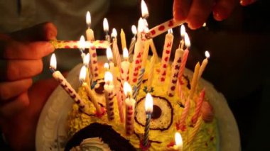 Doğum günü partisinde eller karanlıkta kek üzerine mumlar yanan yakın çekim.