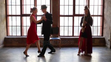 Kız saksofon çalıyor ve çift tango dans büyük pencere