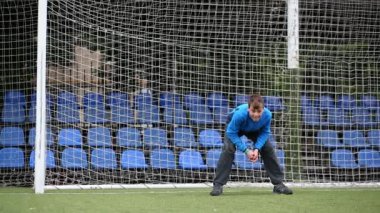 Çocuk kapıda bekleyen bir futbol topu yakalamaya çalışır