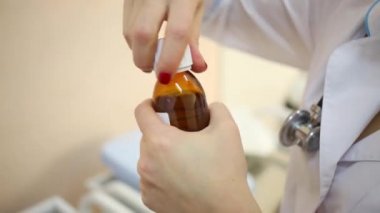 Beyaz önlük doktor şişe tıp şurubu açar.