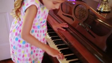 Güzel küçük bir kız üzerinde vintage piyano çalmaya çalışıyor.