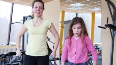 Kızı olan kadın fitness Club dumbbells ile egzersizleri yapmak