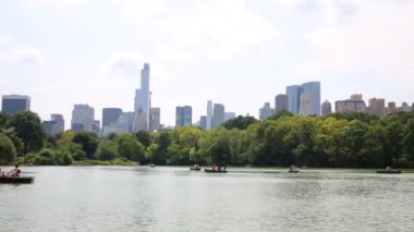 NYC, Amerika Birleşik Devletleri - 21 Ağustos 2014: akla kürekli tekneler New York Central Park ve gökdelenler Manhattan'ın gölet üzerinde dinlenme insanlar.
