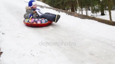 Ormandaki kış günü itibariyle snowtube buz slaytta aşağı mutlu küçük çocuk