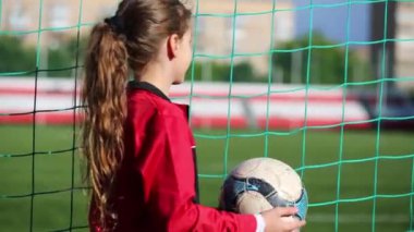 Kız atar ve bir top ve futbol sahasının izlerken yakalar