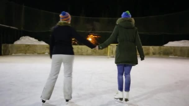 Achterkant Twee Meisjes Tieners Schaatsen Spinnen Ijsbaan Bij Winternacht — Stockvideo