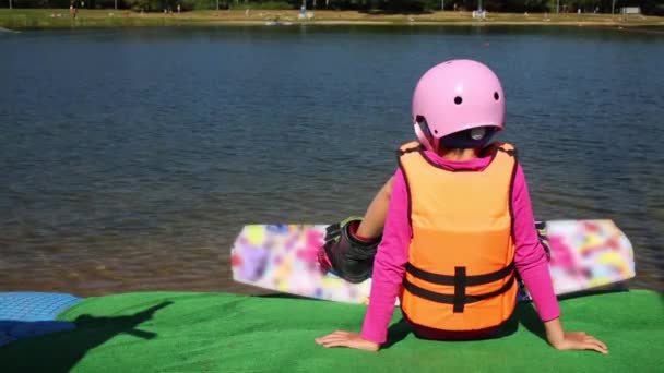 Menina Colete Salva Vidas Capacete Wakeboard Pernas Situadas Frente Lago — Vídeo de Stock