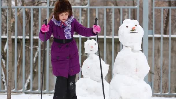 Flicka Skidåkning Nära Två Snögubbar Snöfall Vintern — Stockvideo