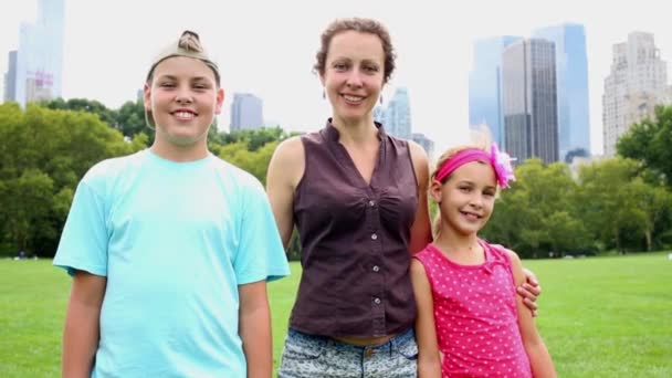 Smiling Woman Two Children Stand Grassy Lawn Skyscrapers Background — Stock Video