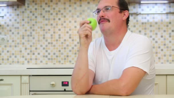 戴眼镜和白色 T恤的男士吃绿色苹果 — 图库视频影像
