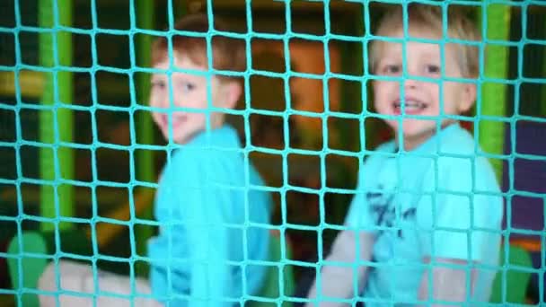 Zwei Glückliche Kleine Jungen Rutschen Hinter Netz Auf Spielplatz Fokus — Stockvideo