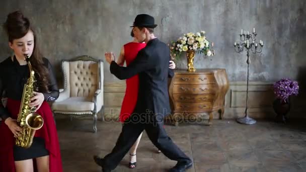 Par Som Dansar Tango Rummet Bredvid Flicka Spela Saxofon — Stockvideo