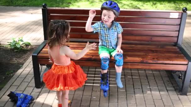 Девочка Играет Мальчиком Сидящим Скамейке Шлеме — стоковое видео