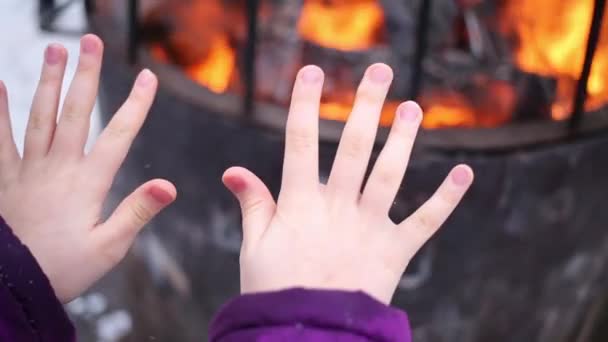 关闭的女孩的手温暖自己的户外火灾 — 图库视频影像