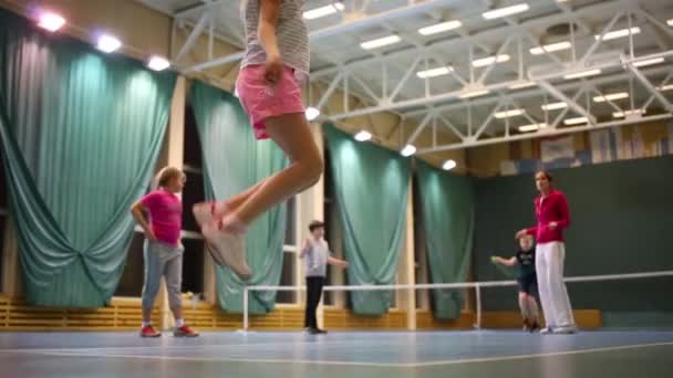孩子们在体育大厅里和老师跳绳 专注于穿粉红色短裤的女孩 — 图库视频影像