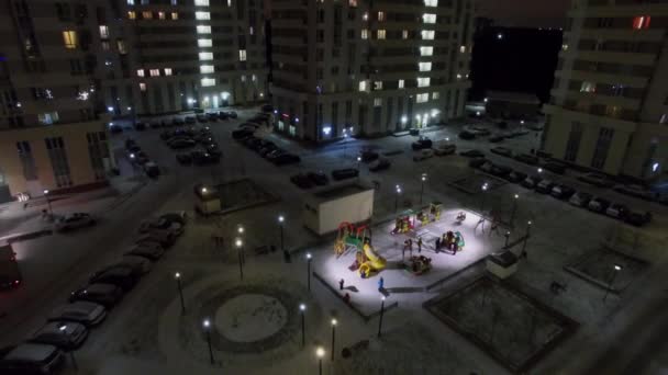 在冬季晚上 在麋鹿岛上的住宅建筑群附近的冰雪覆盖的院子操场 鸟瞰图 — 图库视频影像