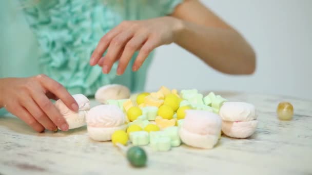Handen Van Meisje Raakt Vele Gele Witte Snoepjes Tafel — Stockvideo
