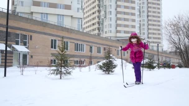 Meisje Kind Roze Skiën Tijdens Sneeuwval Buurt Van Residentiële Gebouwen — Stockvideo