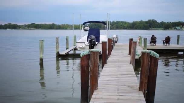 Pier Mit Sitzenden Menschen Stillen See Mit Boot Und Segelbooten — Stockvideo