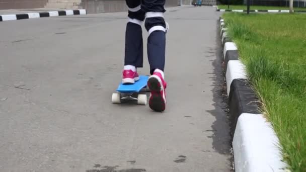 スケート ボードの女の子が庭でアスファルトの足をプッシュ — ストック動画