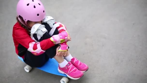 Bir Kaykay Üzerinde Oturan Dizlerinin Sarılma Kız — Stok video