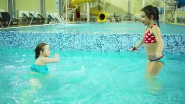 两个女孩在泳衣室内泳池中与纯净水跳舞 — 图库视频影像