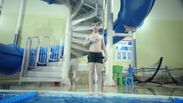 小男孩跳入室内游泳池用蓝色纯净的水 — 图库视频影像