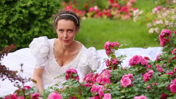 Mulher Morena Vestido Branco Sentado Grama Parque Entre Rosas Cheirando — Vídeo de Stock