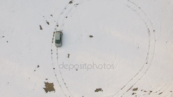 Αυτοκίνητο Οδηγεί Από Χιόνι Και Σύρει Στρογγυλά Σχήματα Από Μονοπάτια — Αρχείο Βίντεο