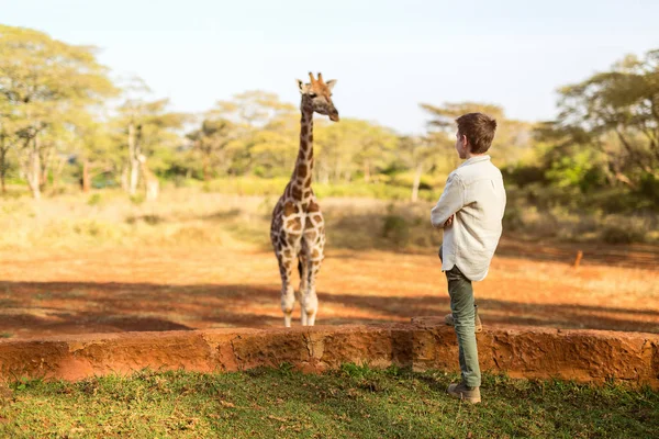 Молодий хлопчик годує жирафа — стокове фото