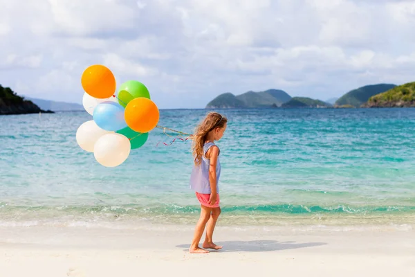 Liten flicka med ballonger på stranden — Stockfoto