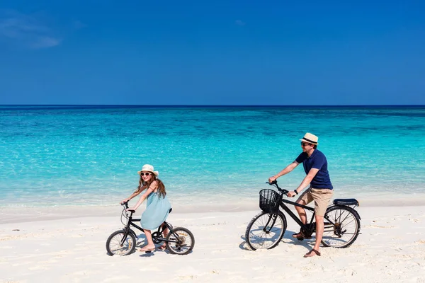 Father and daughter riding bikes at tropical beach — Stock Photo, Image