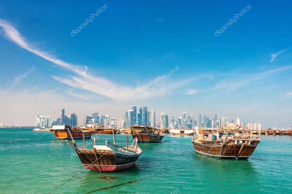 Waterfront in Doha Qatar with traditional wooden small boats known as dhow and city skyline