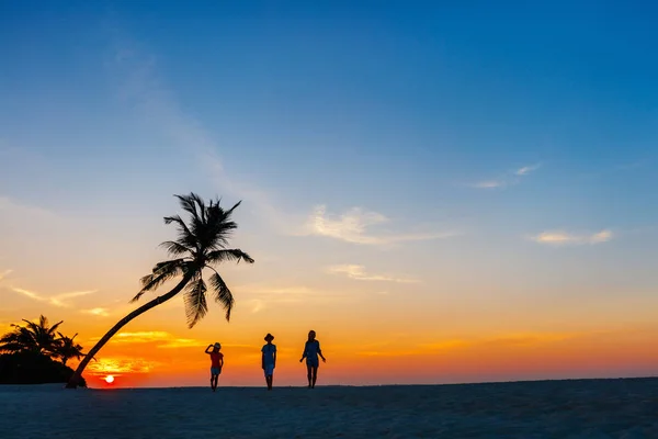 日落时带着两个孩子在热带海滩的家庭概况 — 图库照片