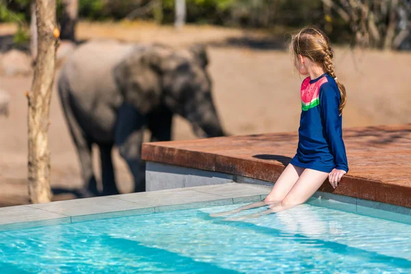 野生動物のスイミング プールの近くに立っているを観察を楽しんでいるアフリカのサファリ バカンス少女 — ストック写真