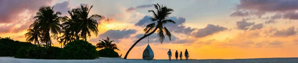 美丽的家庭的剪影四与孩子在热带海滩在日落期间 全景相片完美为横幅 — 图库照片
