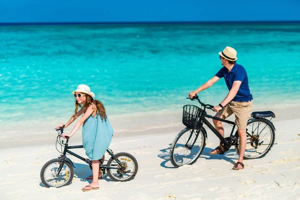 父と一緒に楽しんで熱帯のビーチで自転車に乗って彼女の小さな娘 — ストック写真