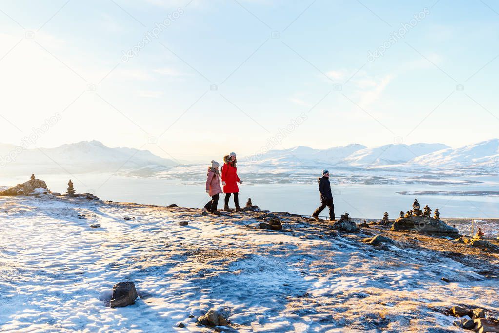 Beautiful family of mother and kids have a pleasant time on snowy winter day outdoors enjoying views near Tromso Norway