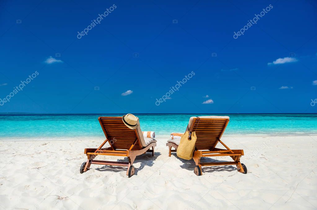 Wooden lounge chairs on a beautiful tropical beach at Maldives